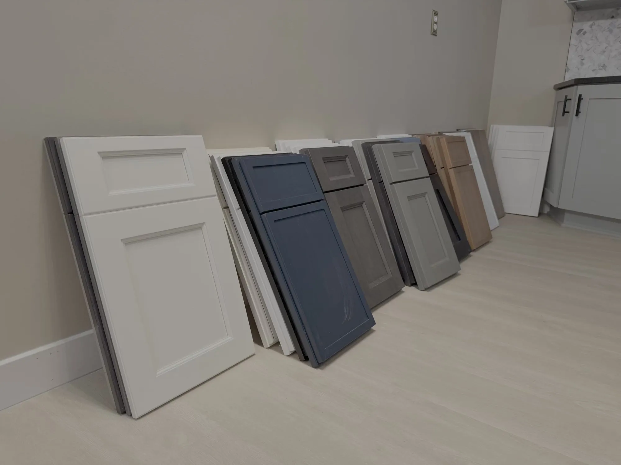 Cabinet door samples in white, navy, gray, and wood finishes